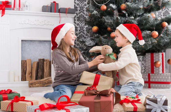 Glückliche Kinder in Weihnachtsmützen beim Auspacken von Weihnachtsgeschenken — Stockfoto