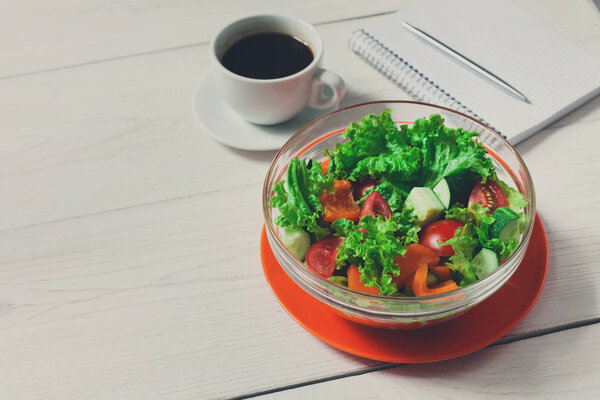 Healthy eating in office, vegetable salad bowl and coffee