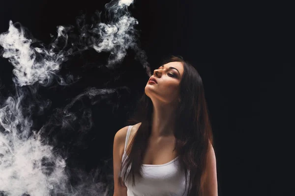 Młoda kobieta vaping e papierosa dymem na czarny — Zdjęcie stockowe
