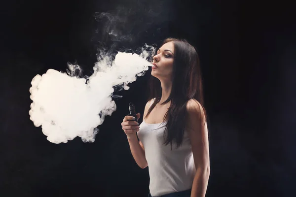 Jovem mulher vaping e-cigarro com fumaça em preto — Fotografia de Stock