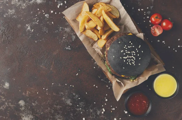 Чорний бургер з картопляними клинами зверху — стокове фото