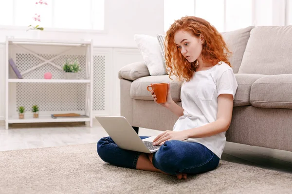 Jonge roodharige meisje met laptop zittend op de vloer — Stockfoto