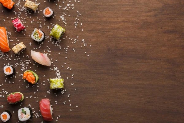 Sushi, maki a rohlíky se sezamem na dřevěné rustikální pozadí, kopírování prostor — Stock fotografie