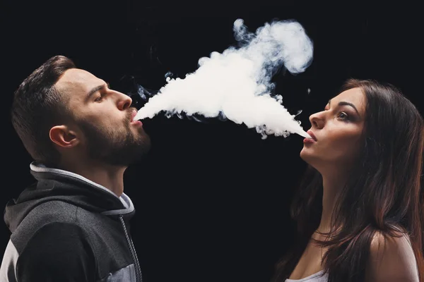 Pareja joven vapeando cigarrillo electrónico con humo en primer plano negro — Foto de Stock