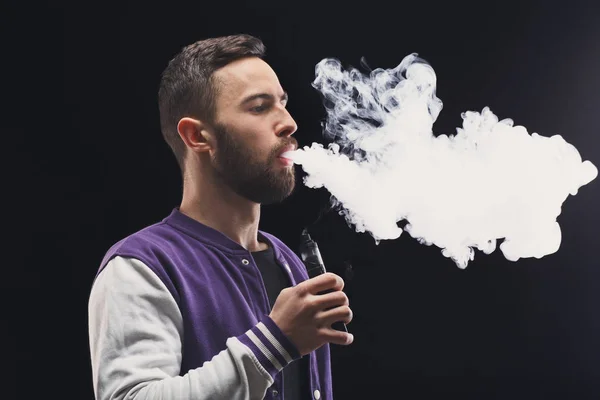 Młody mężczyzna vaping e papierosa dymem na czarny — Zdjęcie stockowe