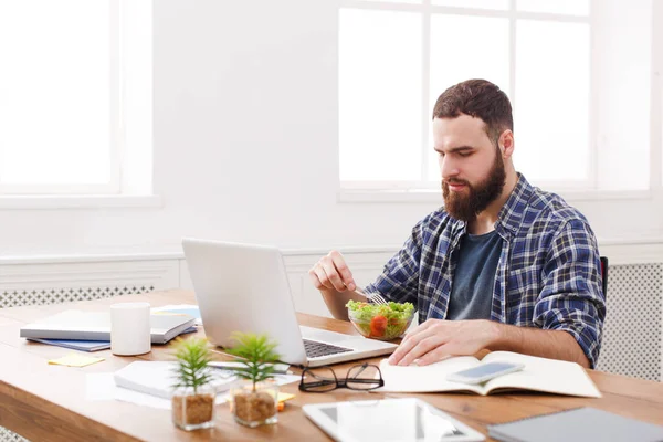 Busy man has business lunch in modern office interior