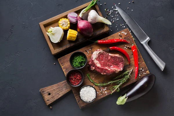 Rib eye steak with spices on wooden desk and diverse cooking ingredients in wooden box. — Stock Photo, Image