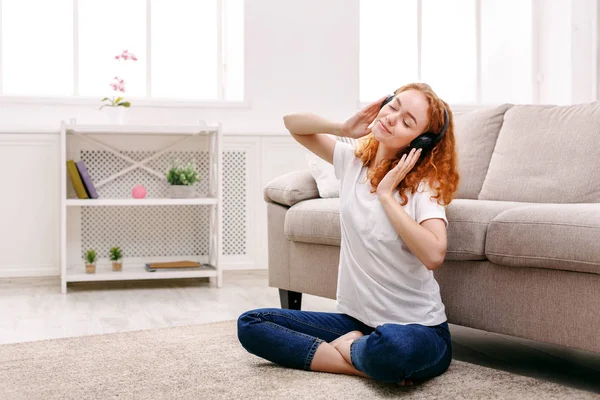 Jonge vrouw in de koptelefoon op de vloer — Stockfoto