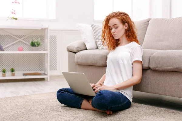 Katta oturan dizüstü bilgisayar ile genç Kızıl saçlı kız — Stok fotoğraf