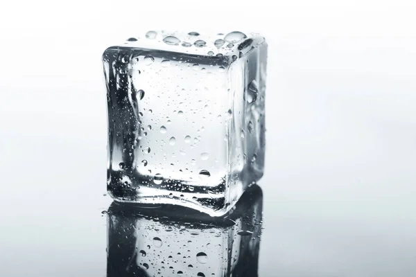 Transparent ice cube with reflection on white — Stock Photo, Image