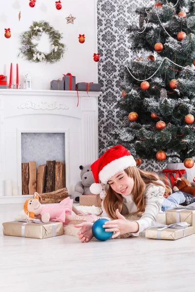 Bella ragazza in cappello di Babbo Natale scartando regali di Natale — Foto Stock