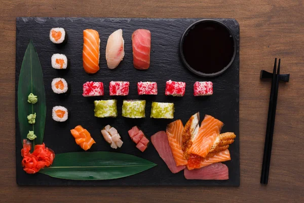 Sada sushi maki a rohlíky na černé rustikální dřevo, horní pohled — Stock fotografie