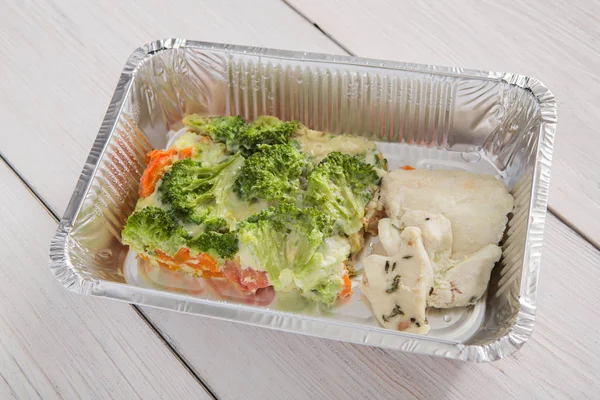 Healthy food take away, broccoli in foil box on wood background