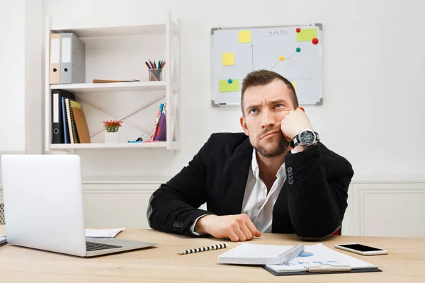 Jonge verveeld zakenman met laptop in moderne witte kantoor — Stockfoto