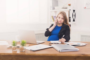 Hamile iş kadını telefonda konuşurken iş başında