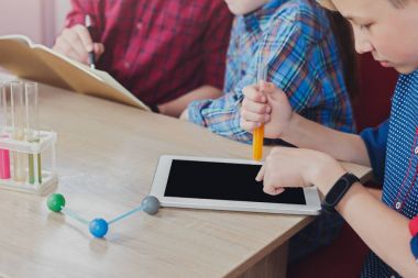 Tablet ve laboratuar ekipmanları ile okuyan çocuk