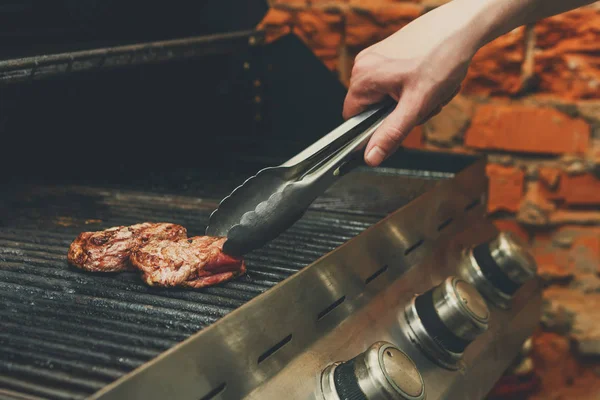 Homem cozinhar bifes de carne em churrasqueira profissional ao ar livre — Fotografia de Stock