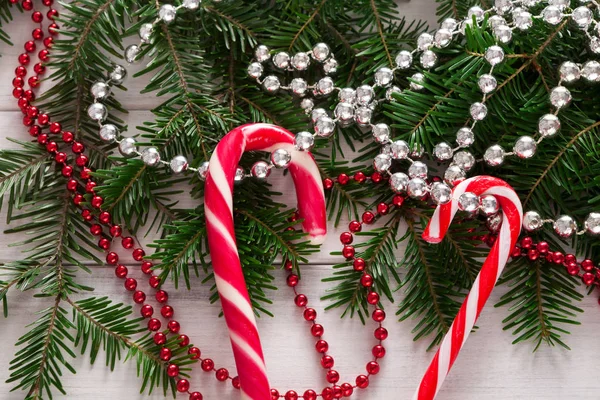 Sfondo natalizio con caramelle e bordo abete su legno — Foto Stock