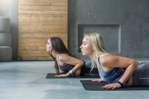 Las mujeres jóvenes en la clase de yoga, serpiente pose estiramiento — Foto de Stock