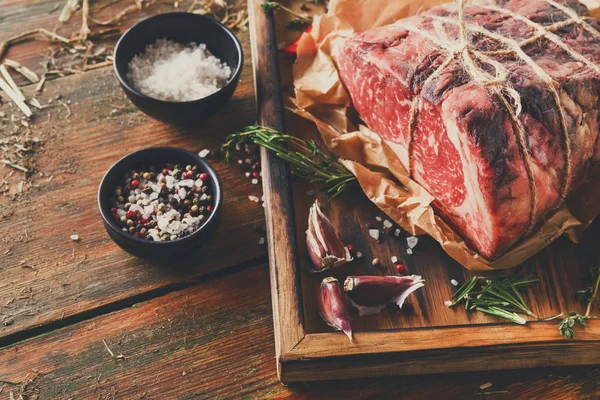 Raw aged prime black angus beef in craft papper on rustic wood — Stock Photo, Image