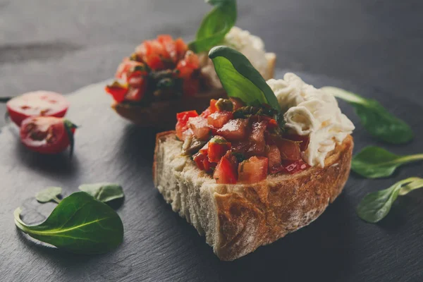 Bruschetta com queijo e legumes sobre fundo preto — Fotografia de Stock