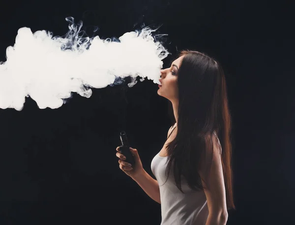 Mujer joven vapeando e-cigarrillo con humo en negro — Foto de Stock