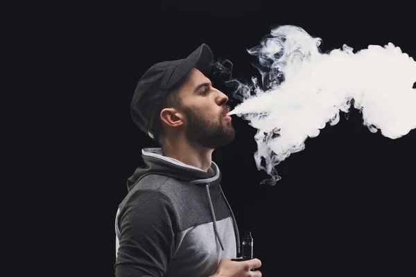 Homem jovem vaping e-cigarro com fumaça em preto — Fotografia de Stock