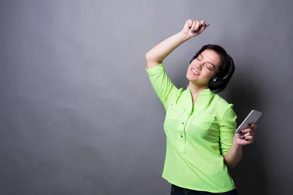 Mulher com olhos fechados curtindo música em fones de ouvido — Fotografia de Stock