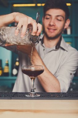 Genç barmen kokteyl içki cam içine dökme