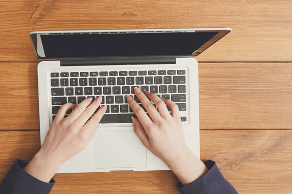 Female using laptop in coffee shop, close-up, top view