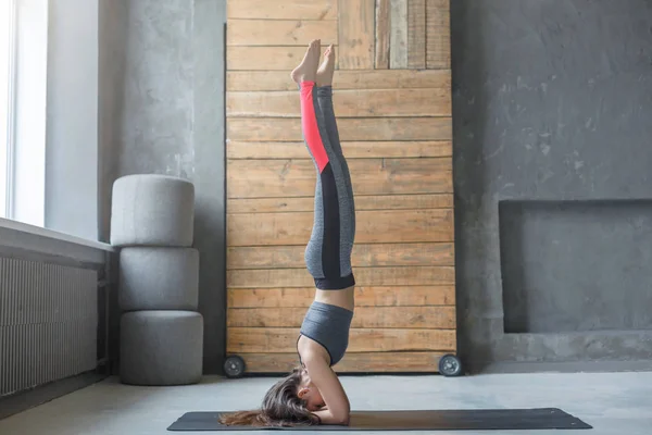 Junge Frau im Yoga-Kurs macht Kopfstand — Stockfoto