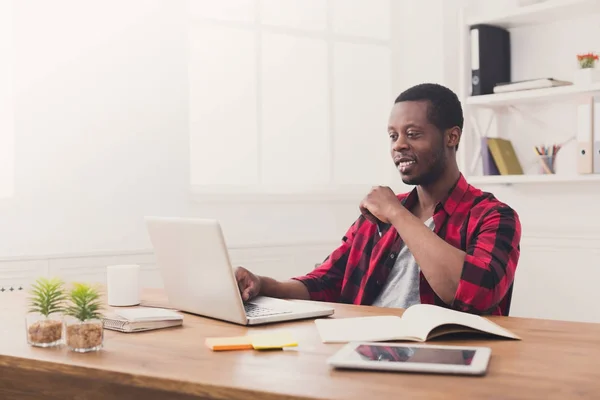 Happy black podnikatel v běžné kanceláři, práce s notebookem — Stock fotografie
