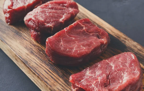 Raw beef filet mignon steaks on wooden board at gray background — Stock Photo, Image