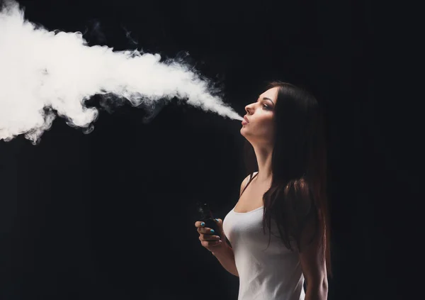 Mujer joven vapeando e-cigarrillo con humo en negro — Foto de Stock