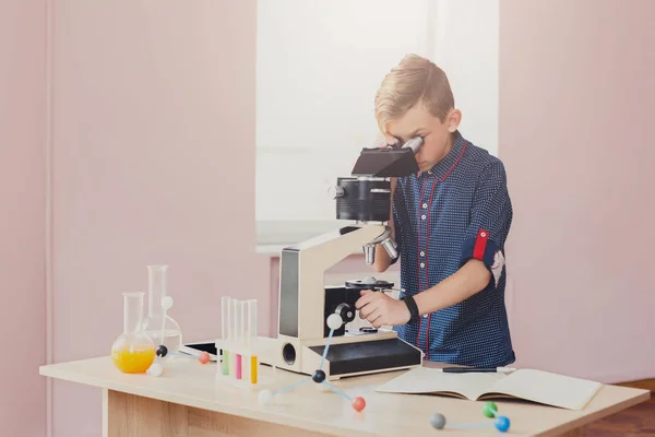 Colegial mirando al microscopio en la lección —  Fotos de Stock