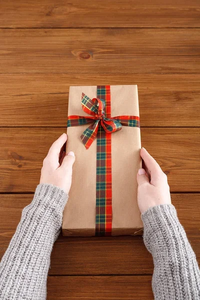 Womans hands give christmas gift in present box
