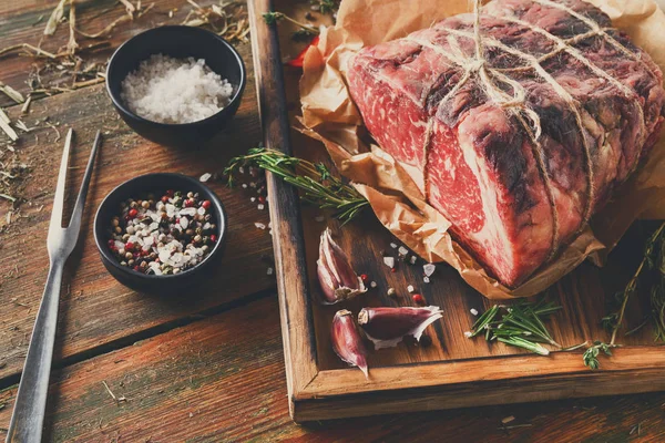 Raw aged prime black angus beef in craft papper on rustic wood — Stock Photo, Image