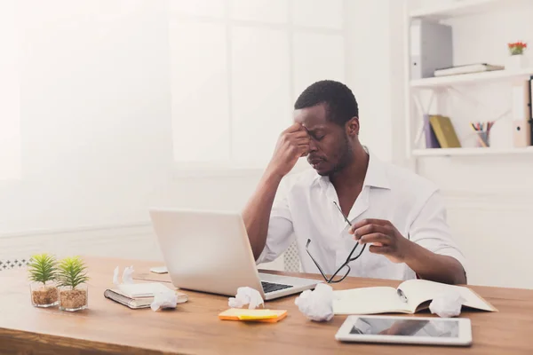 Tired african-american employee in office, work with laptop