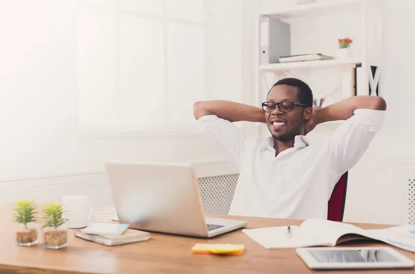 Homem de negócios preto relaxado com laptop no escritório branco moderno — Fotografia de Stock