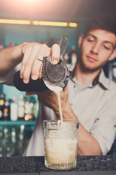Camarero joven vertiendo bebida de cóctel en el vaso — Foto de Stock