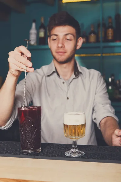 Joven barman guapo vertiendo cóctel en el vaso — Foto de Stock