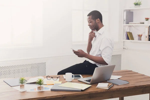 Молодий чорний бізнесмен з мобільним в сучасному білому офісі — стокове фото