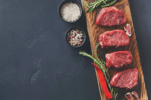 Filet mignon steaks and spices on wood at black background — Stock Photo, Image