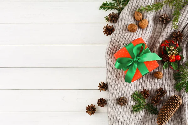 Різдвяні подарунки на фоні столу з білого дерева. Шарф, різдвяна коробка, ялинкова гілка — стокове фото