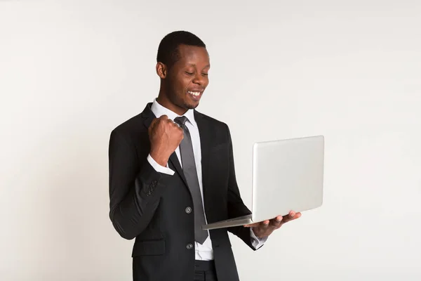 Hombre negro sonriente gerente en traje de pie, sosteniendo el ordenador portátil en las manos. Retrato — Foto de Stock