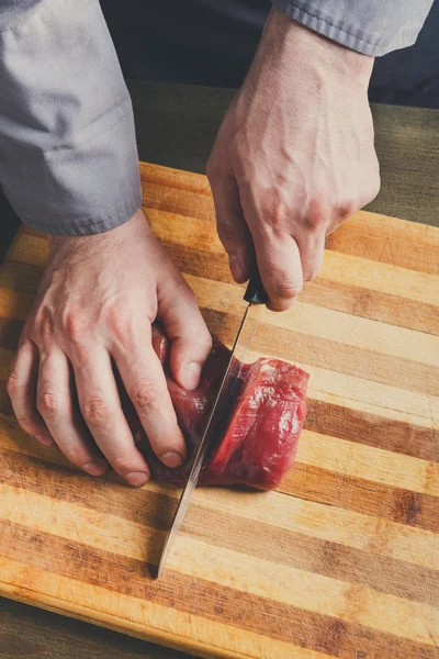 Chef cutting filet mignon on wooden board at restaurant kitchen — Stock Photo, Image