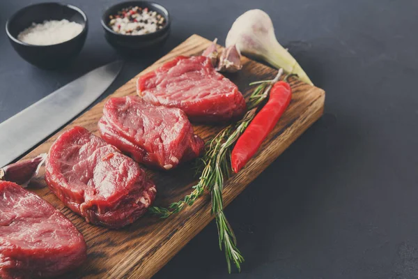 Filet mignon steaks and spices on wood at black background — Stock Photo, Image