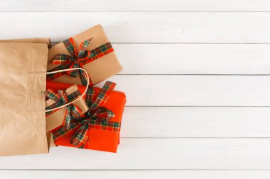 Arka plan beyaz ahşap üzerine kağıt torba içinde yaratıcı Noel hediyeleri masa