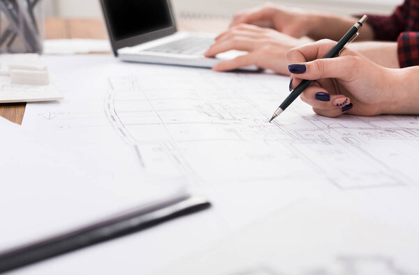 Unrecognizable architects discussing building plan