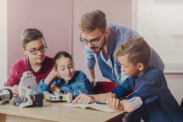 Stem education. Kids creating robots with teacher — Stock Photo, Image